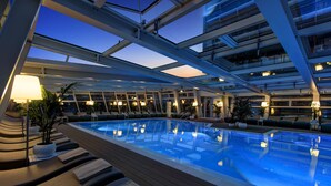 A swimming pool with lounge chairs and potted plants, surrounded by a modern architectural structure with glass railings. - Almar Lido Jesolo Resort & Spa (Jesolo)