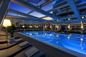 Una piscina techada, una piscina al aire libre de temporada, sombrillas