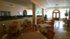 A spacious indoor dining area with multiple tables and chairs, large windows, and a central column. - Best Western Centro Cadereyta (Cadereyta Jimenez)
