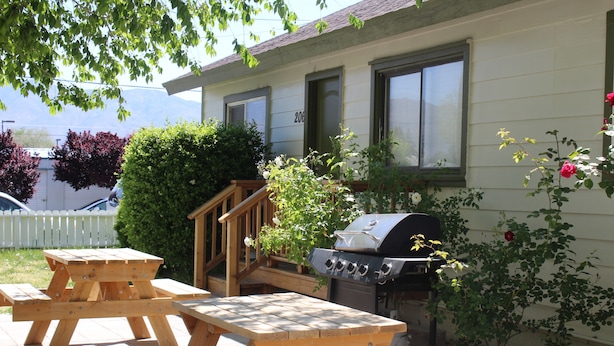 A patio with picnic tables, a grill, and a small staircase leading to a deck.