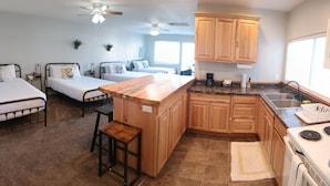 A compact living space with a kitchenette, two beds, and a dining area.