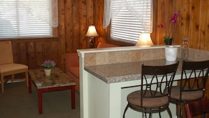 A cozy cabin interior with a dining area, wooden walls, and a small kitchen counter.