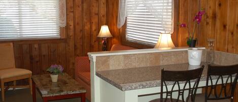 Interior acogedor de una cabaña con comedor, paredes de madera y una pequeña encimera de cocina.