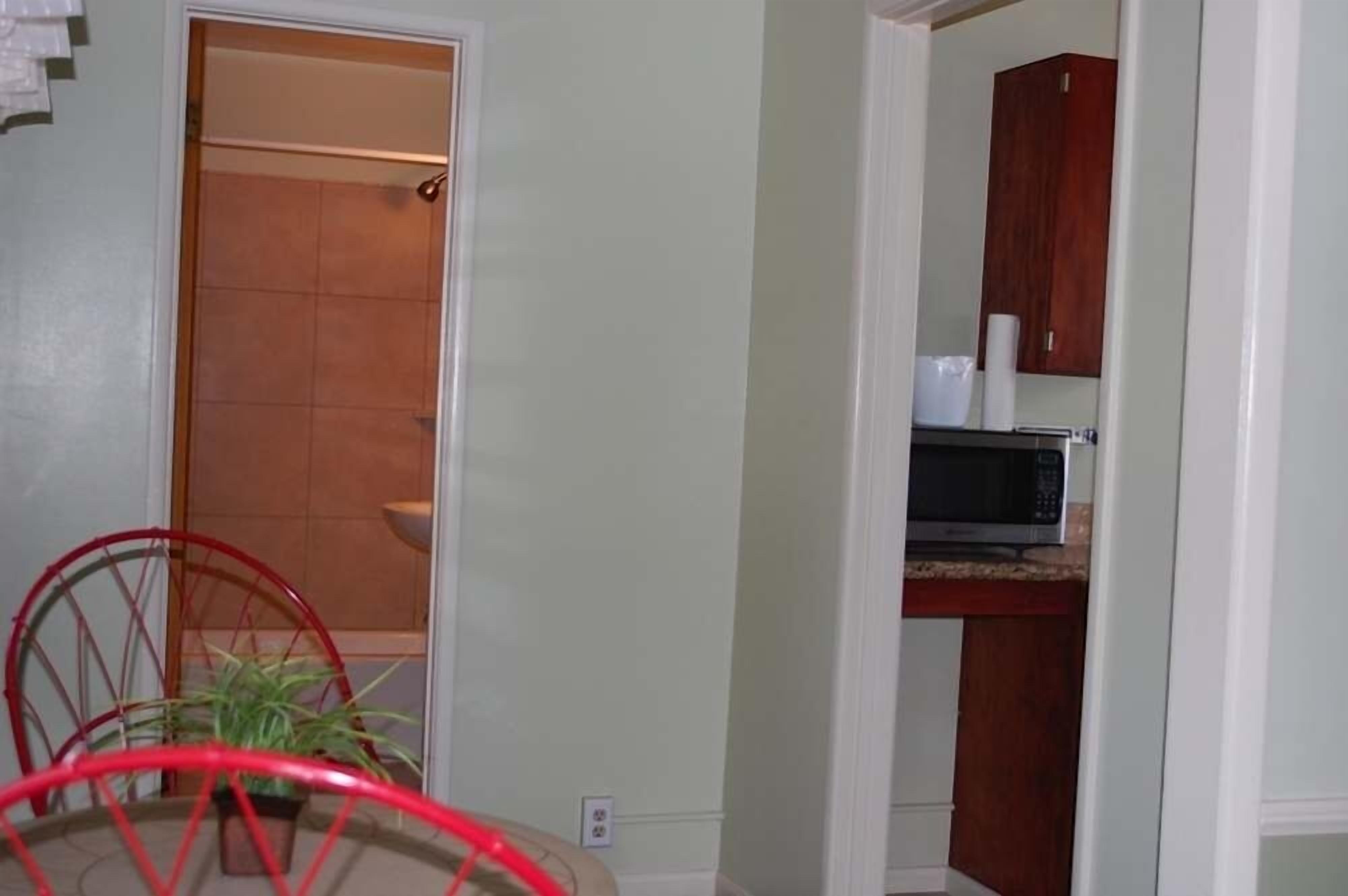 A kitchen with a microwave, cabinets, and a red chair.