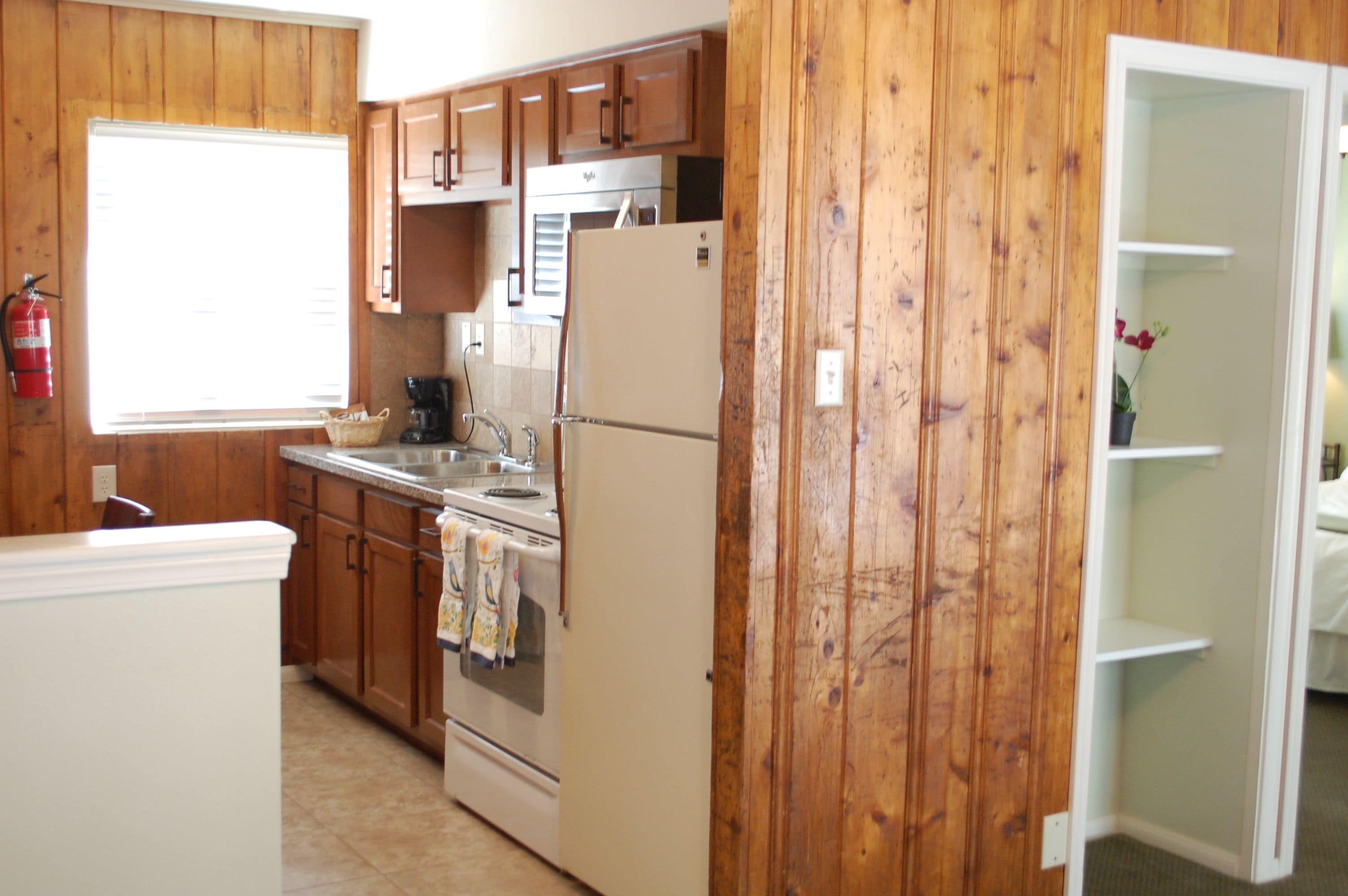 A kitchen with wooden paneling, a refrigerator, stove, and cabinets.