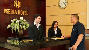 En receptionsdisk på Media Hotel med et ur og en blomsteropsætning.