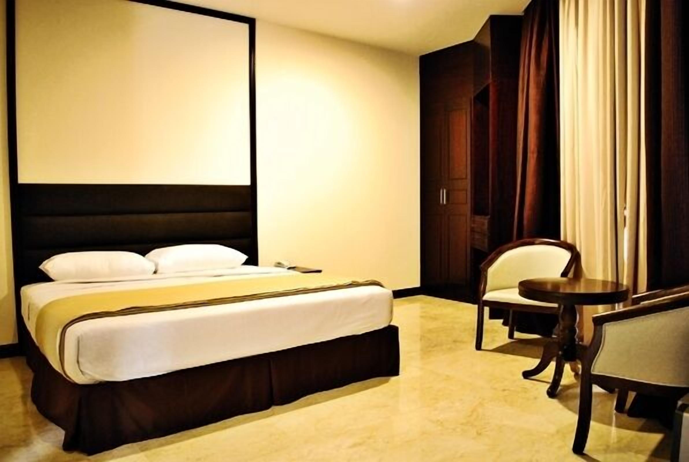Una habitació d'hotel amb un llit gran, un escriptori i una cadira.