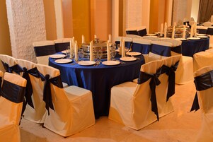 A banquet hall with round tables set for a formal event, each with white chairs and blue tablecloths.