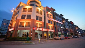 Et hotel med flere etager, et tydeligt skilt med 'Media Hotel & Restoran', flere balkoner og en parkeringsplads med biler.