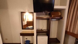 Ein kleines Zimmer mit Etagenbetten, einem Fernseher, einem Schreibtisch mit Spiegel und einem kleinen Kühlschrank.
