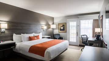 Une chambre d’hôtel avec un grand lit, un bureau, une chaise et une porte donnant sur un balcon.
