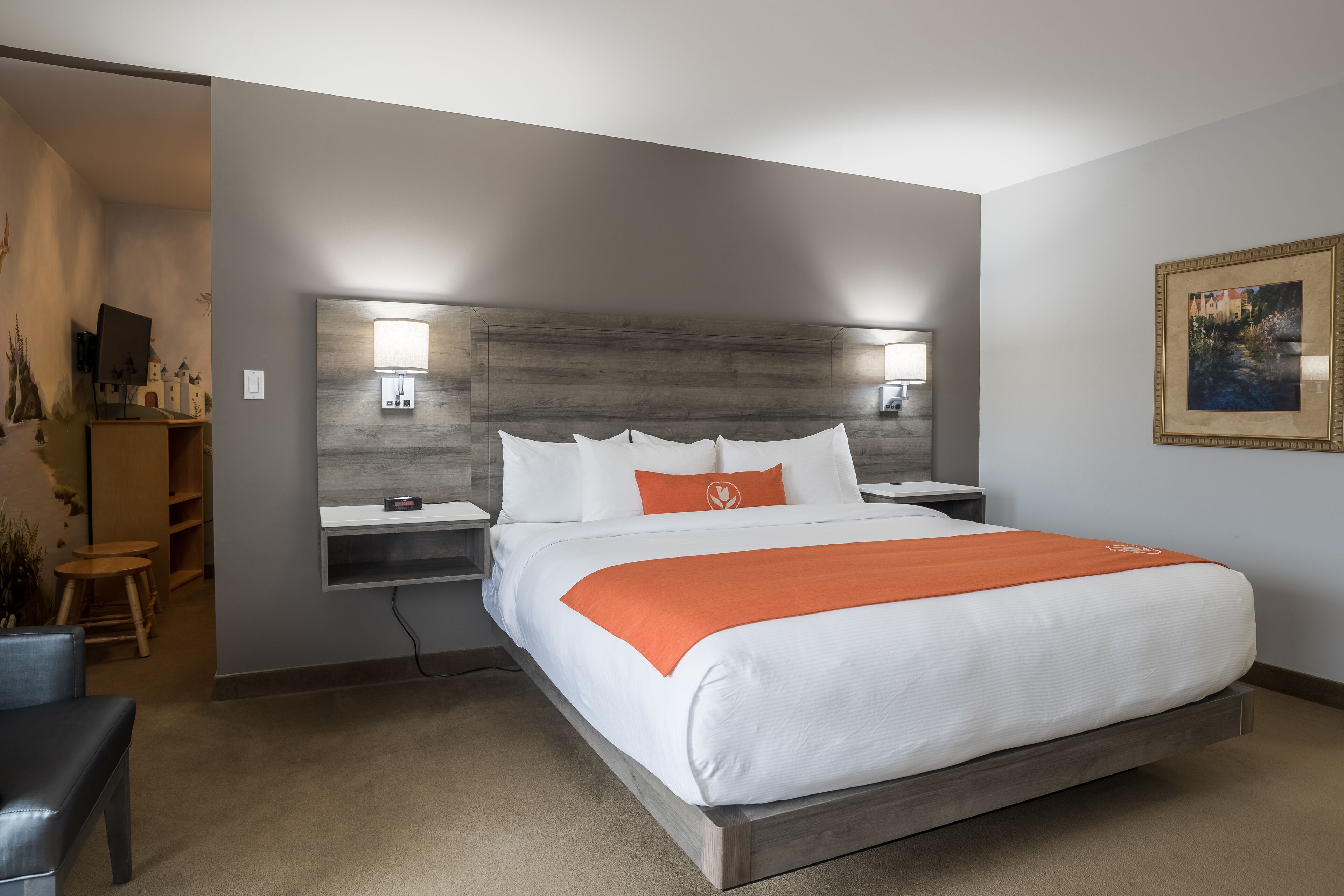 Una habitación de hotel moderna con una cama grande, dos mesitas de noche, un escritorio y una silla.