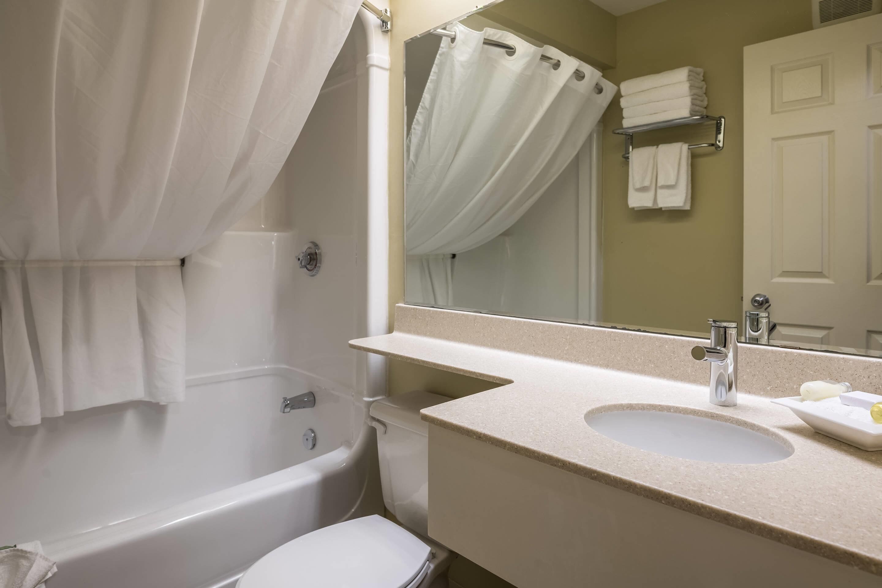 A bathroom with a bathtub, toilet, sink, and a mirror.