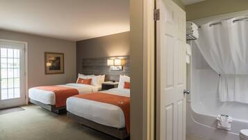 A hotel room with two beds, a bathroom with a bathtub, and a door leading to another room.