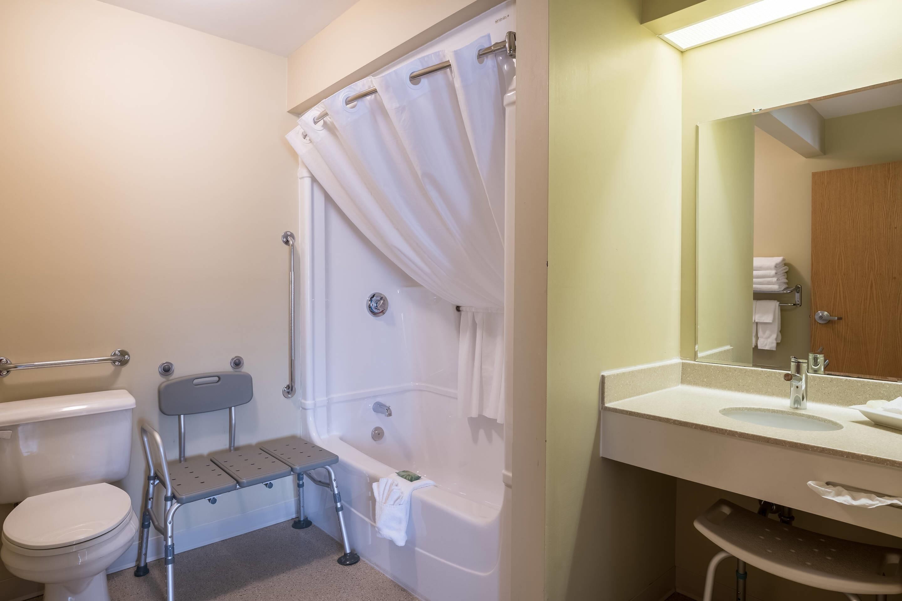 A bathroom with a toilet, a shower with a curtain, a sink, and a mirror.