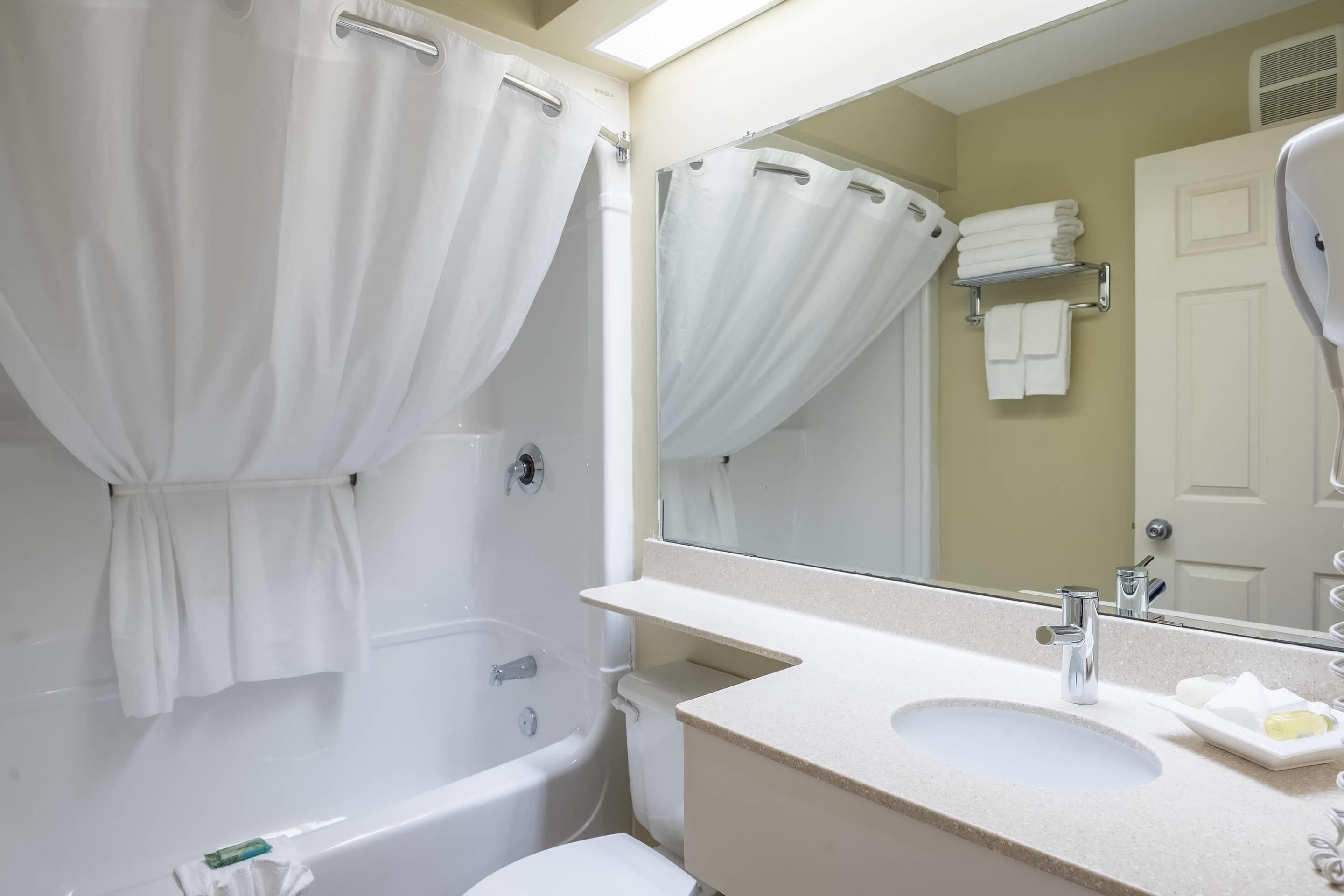 A bathroom with a bathtub, a sink, a mirror, and a towel rack.