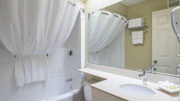 A bathroom with a bathtub, a sink, a mirror, and a towel rack.