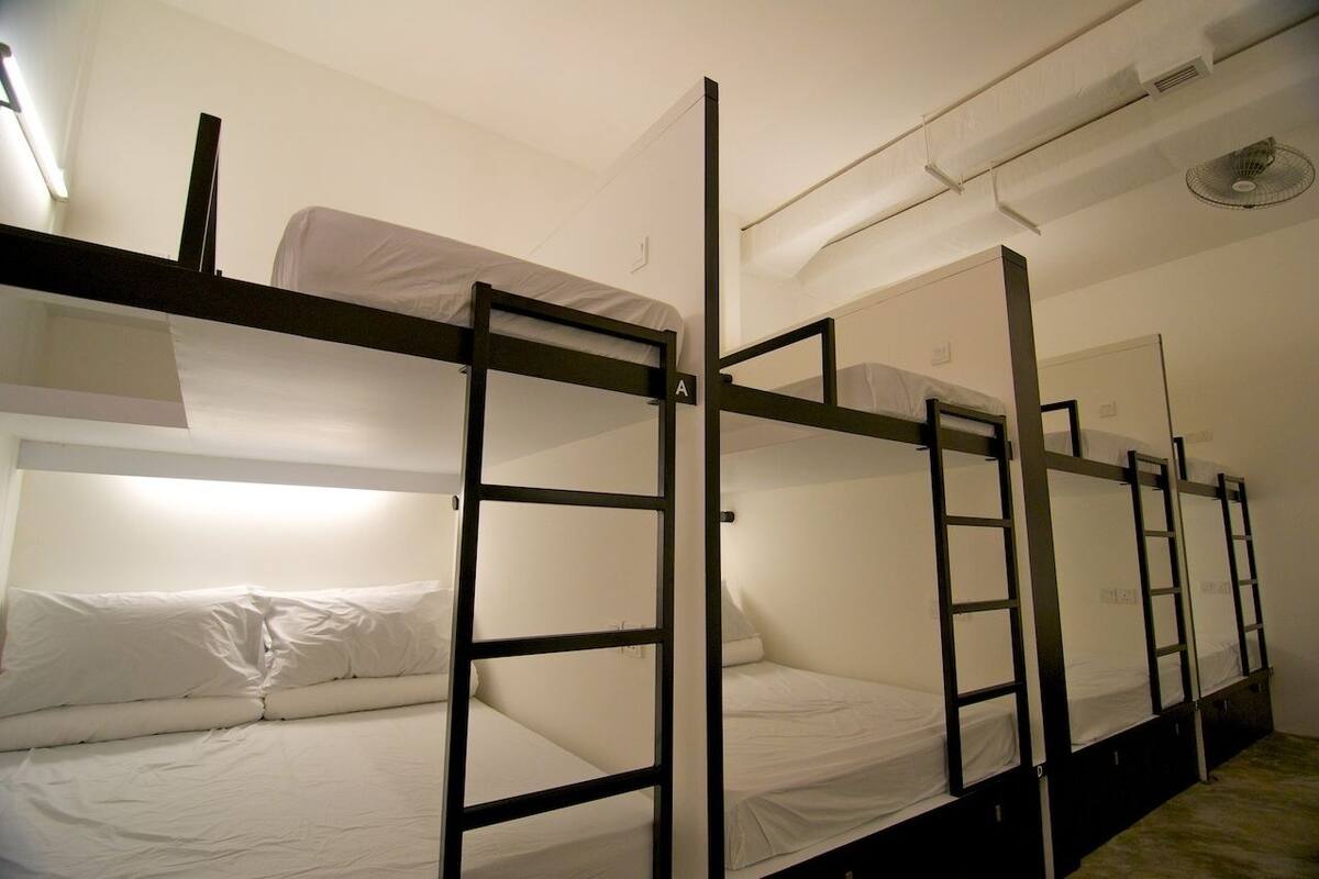 A bunk bed room with white bedding and a ladder.