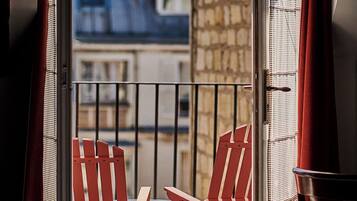 A balcony with red chairs and a view of buildings.