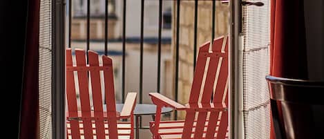 A balcony with red chairs and a view of buildings.