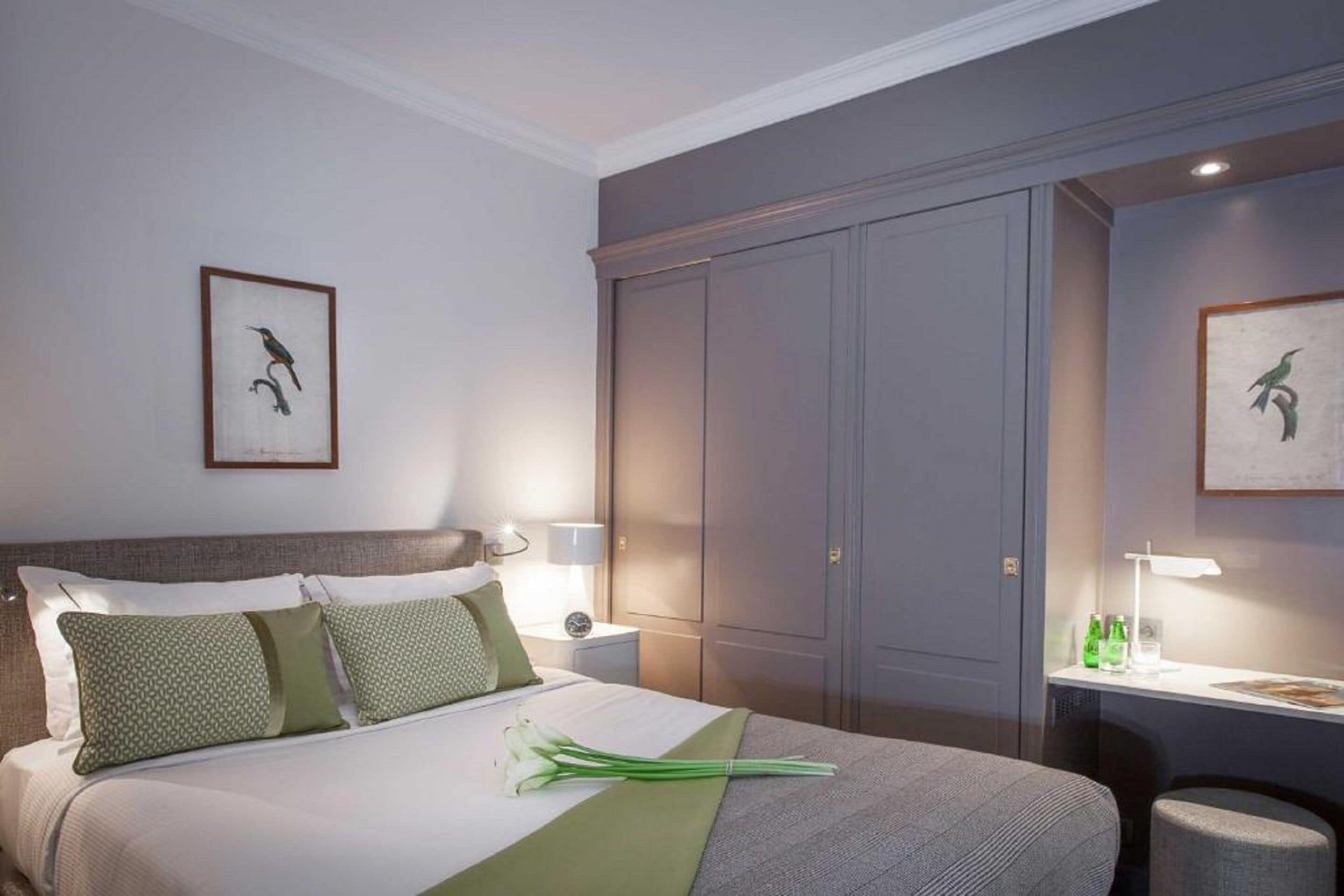A hotel room with a bed, bedside tables, a desk, and a wardrobe.