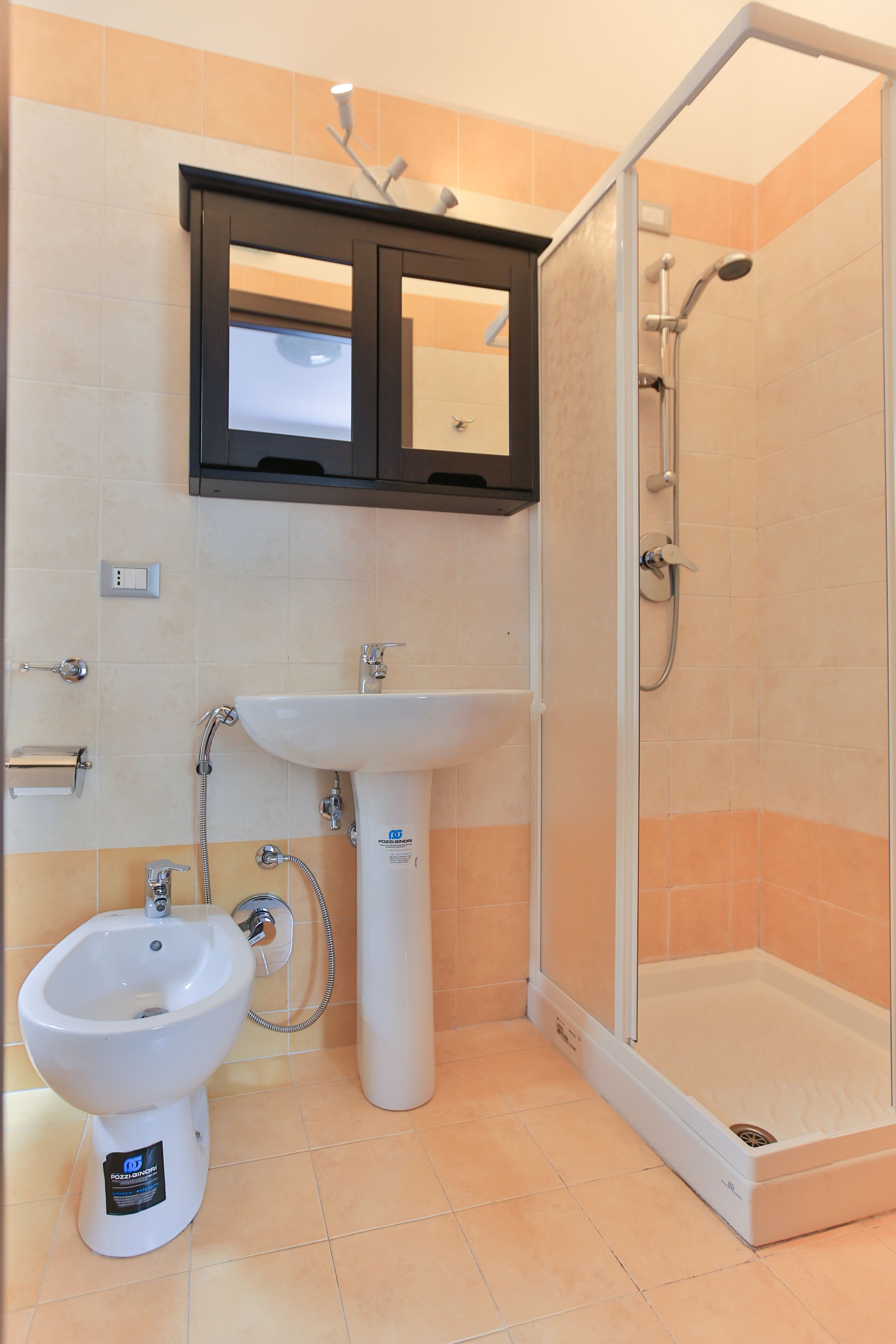 A bathroom with a shower, sink, and bidet.