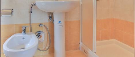 A bathroom with a shower, sink, and bidet.