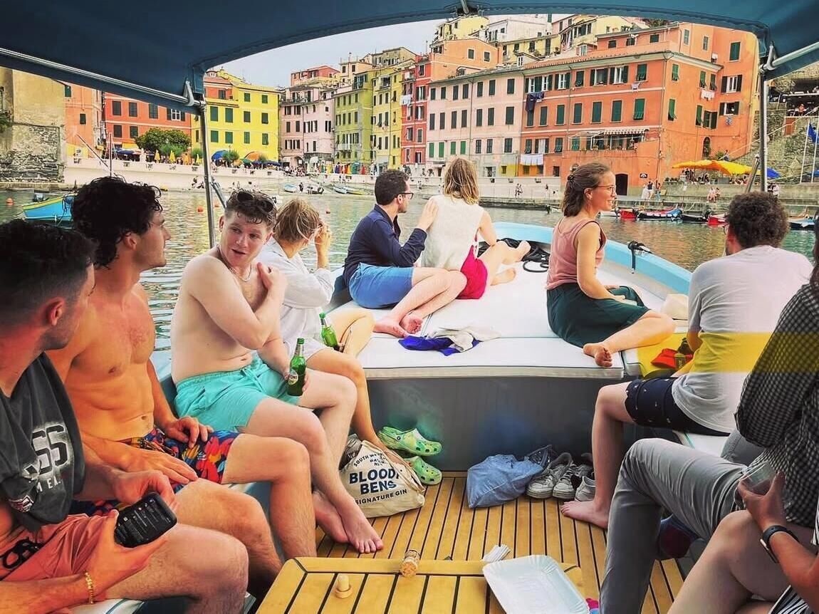 A group of people sitting on a boat with a cityscape in the background.