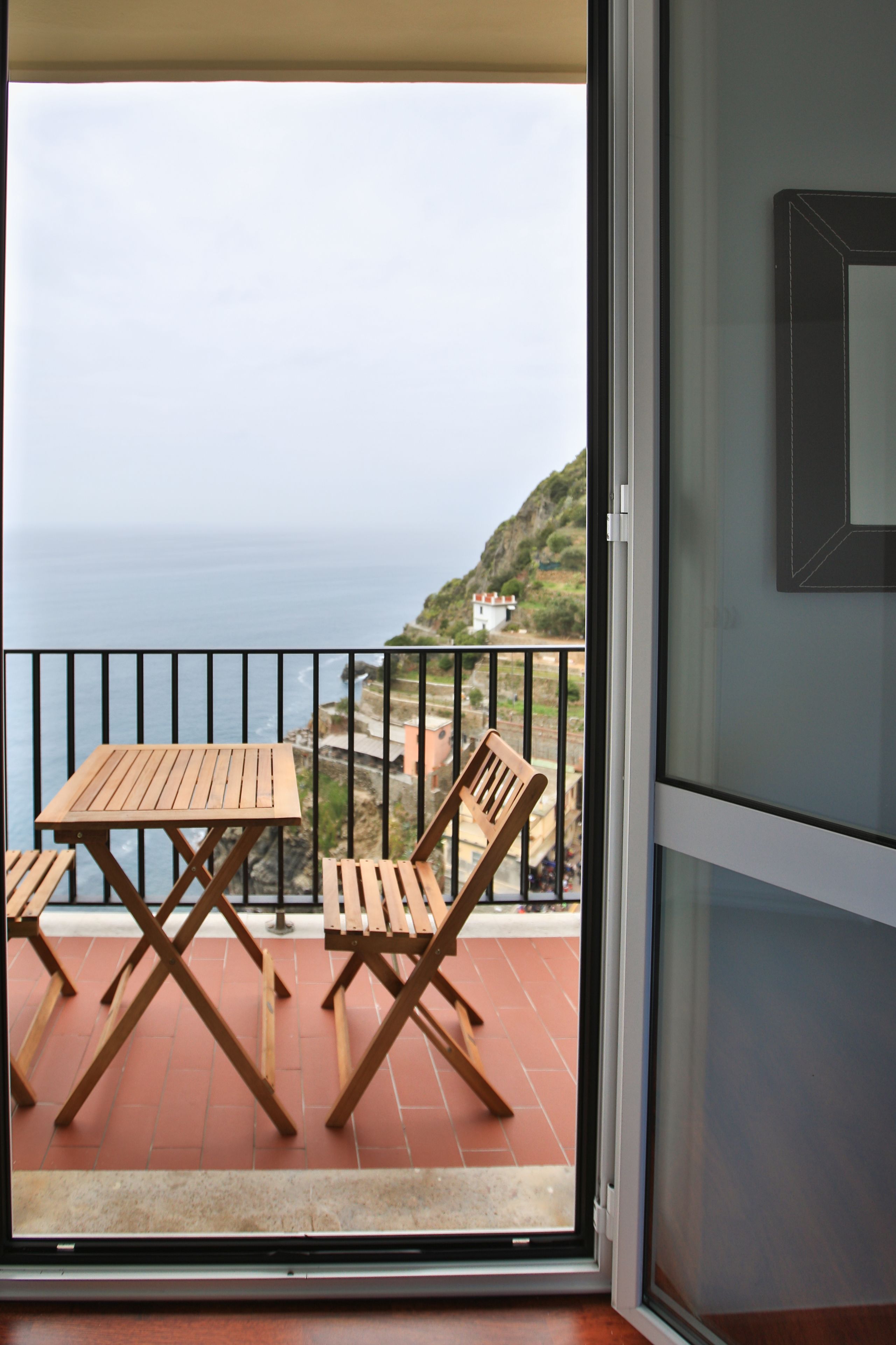 A balcony with wooden furniture and a view of the sea.