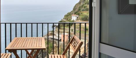 A balcony with wooden furniture and a view of the sea.