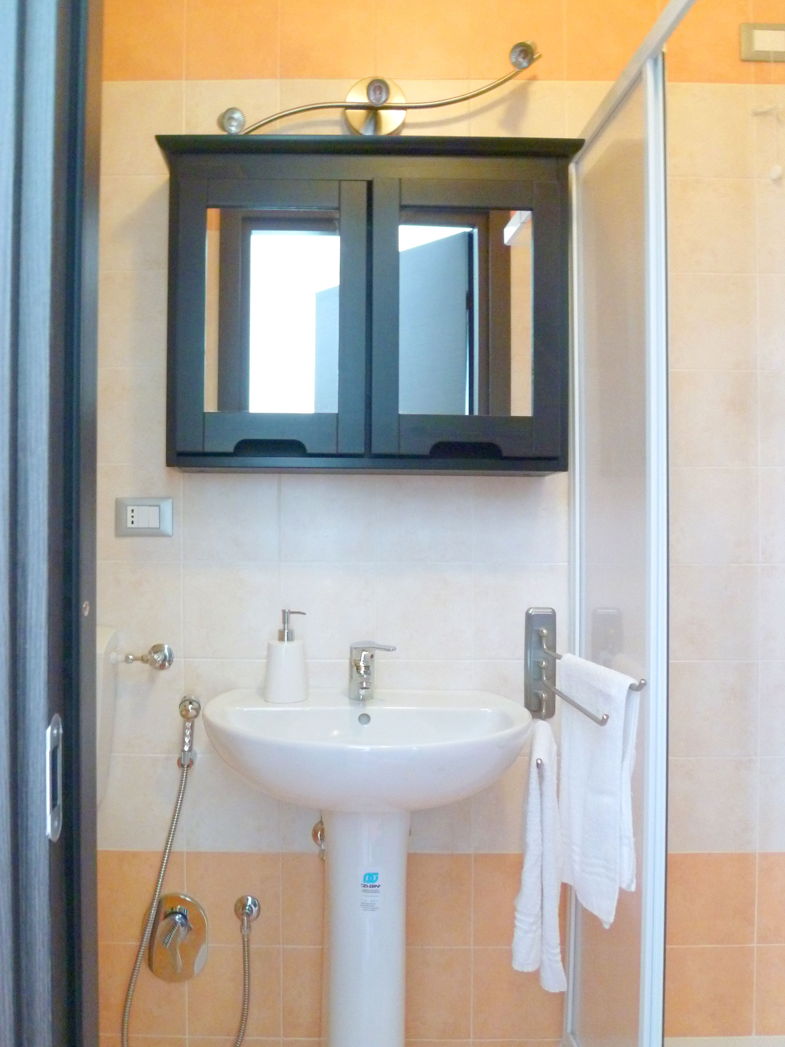 A bathroom with a white sink, a mirror above it, and a shower area.