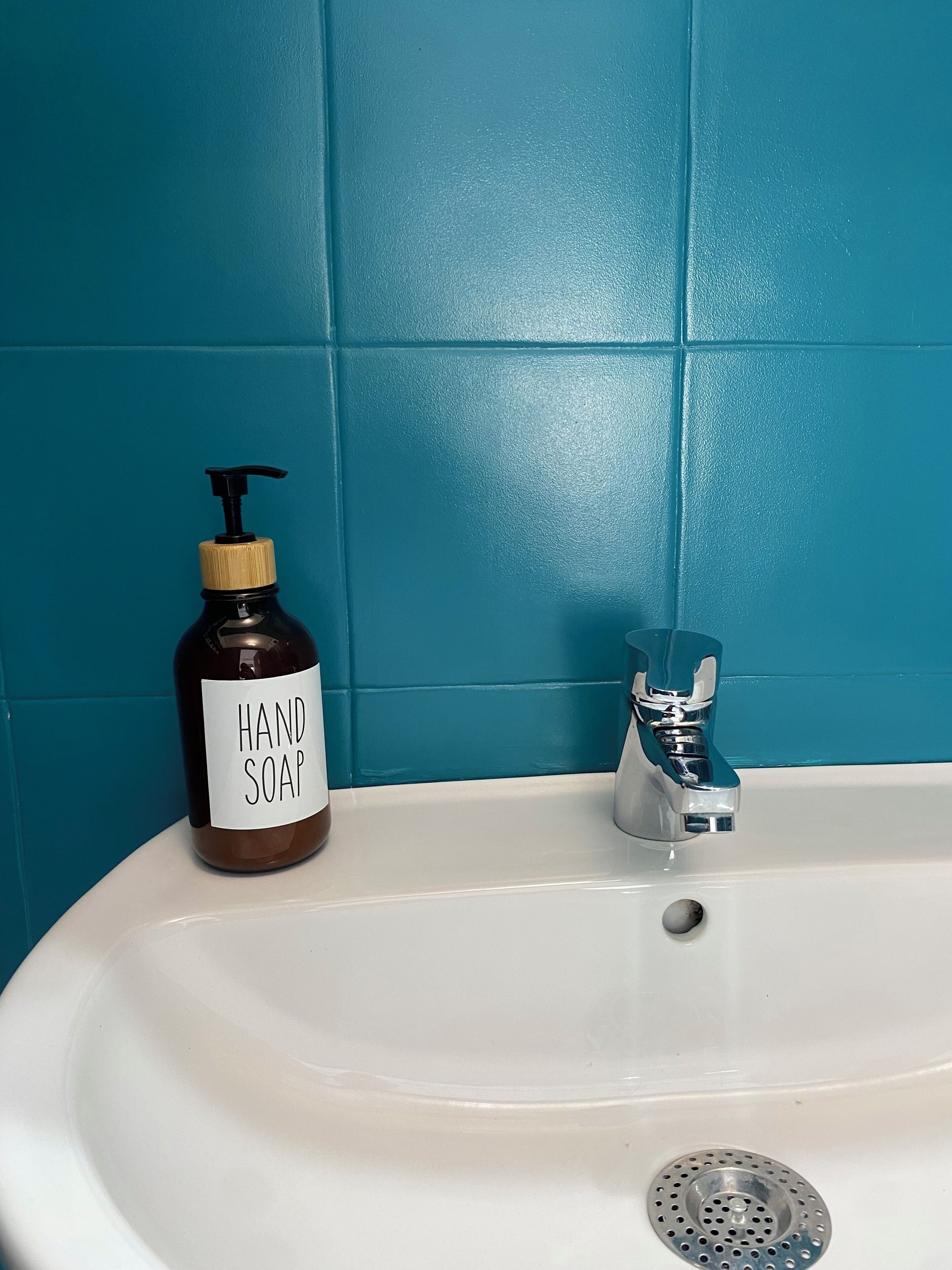 A bathroom sink with a bottle of hand soap and a faucet.