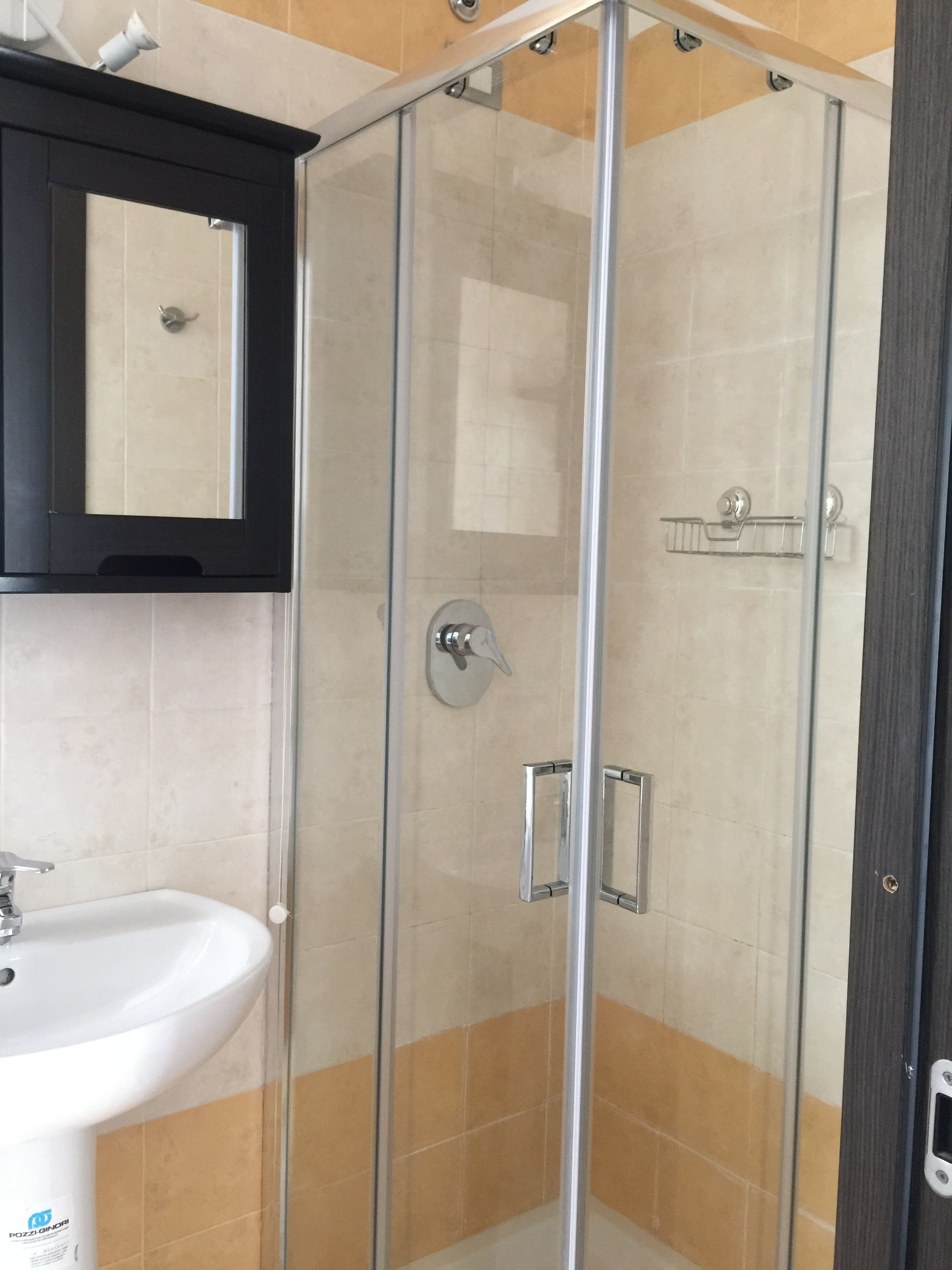 A bathroom with a glass-enclosed shower, a white sink, and a mirror above the sink.