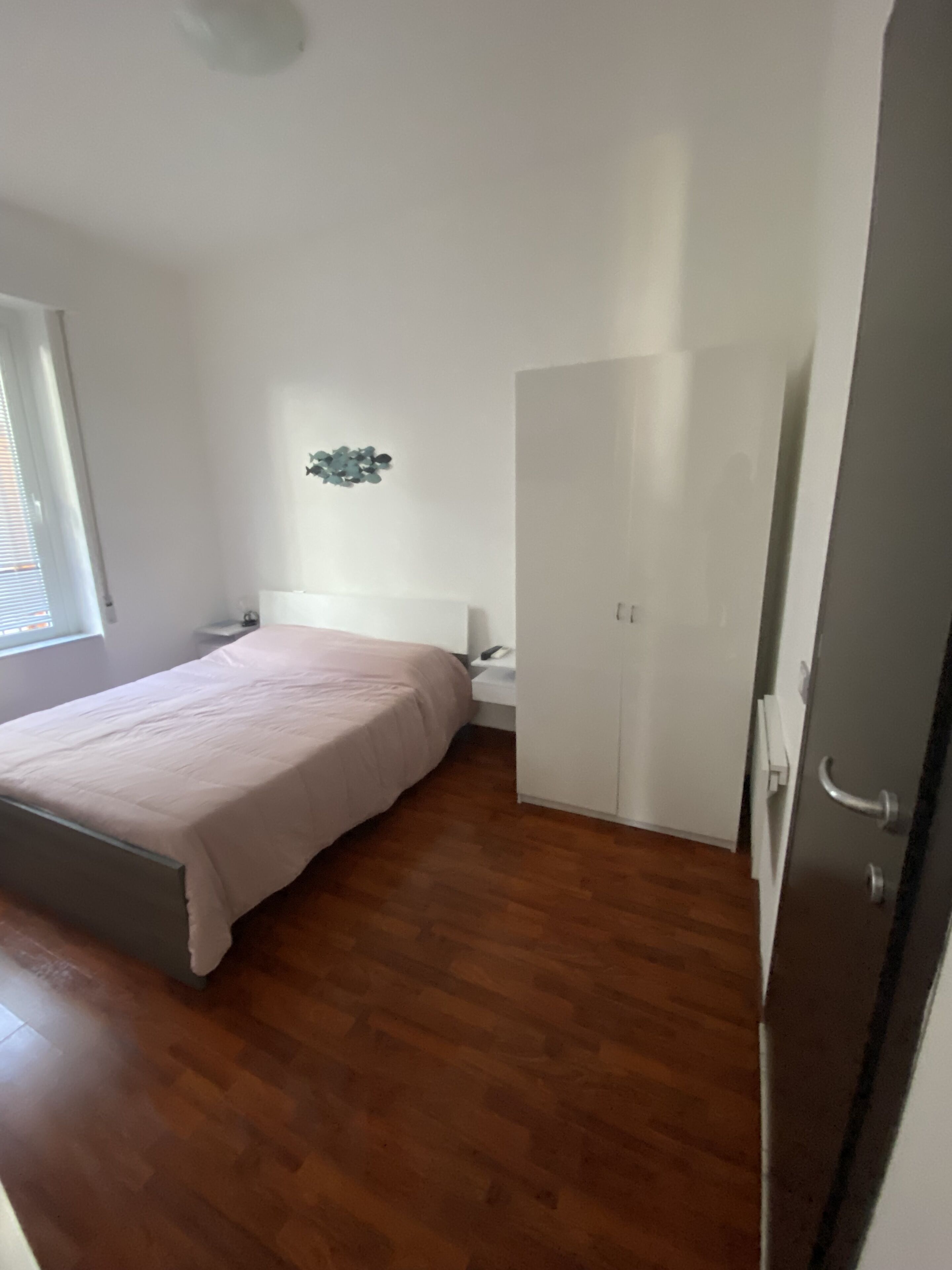 Une chambre à coucher comprenant un lit, une armoire, une table de chevet et un élément décoratif mural.