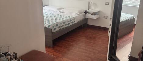 A bedroom with a bed, bedside table, and a small window.