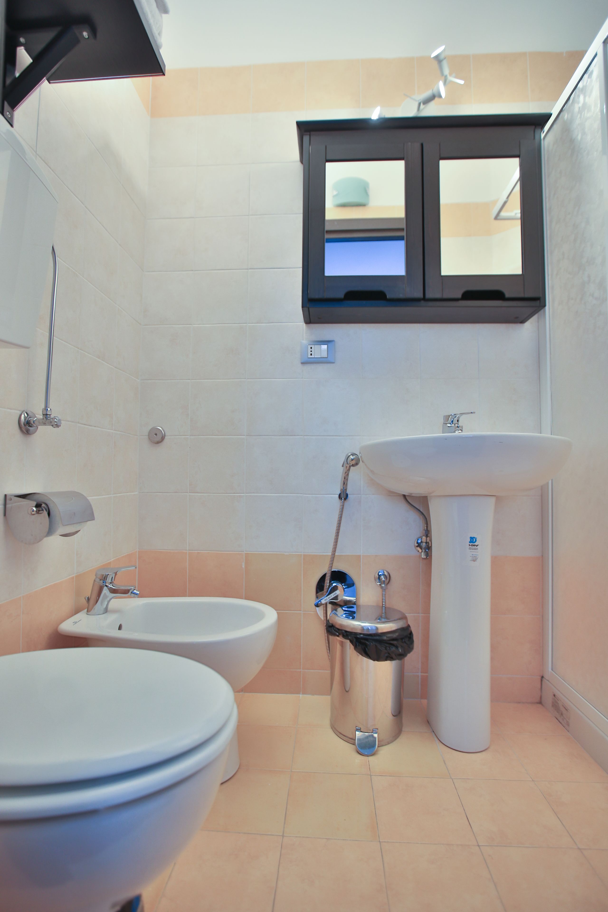 Ein Badezimmer mit Toilette, Bidet, Waschbecken und einem Schrank darüber.
