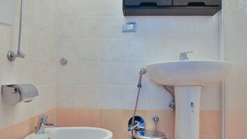 Ein Badezimmer mit Toilette, Bidet, Waschbecken und einem Schrank darüber.