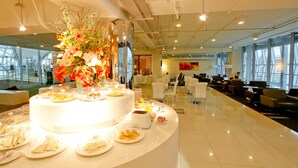Un moderno vestíbulo de hotel con una barra de desayuno central, zona de estar y grandes ventanales que ofrecen vistas.