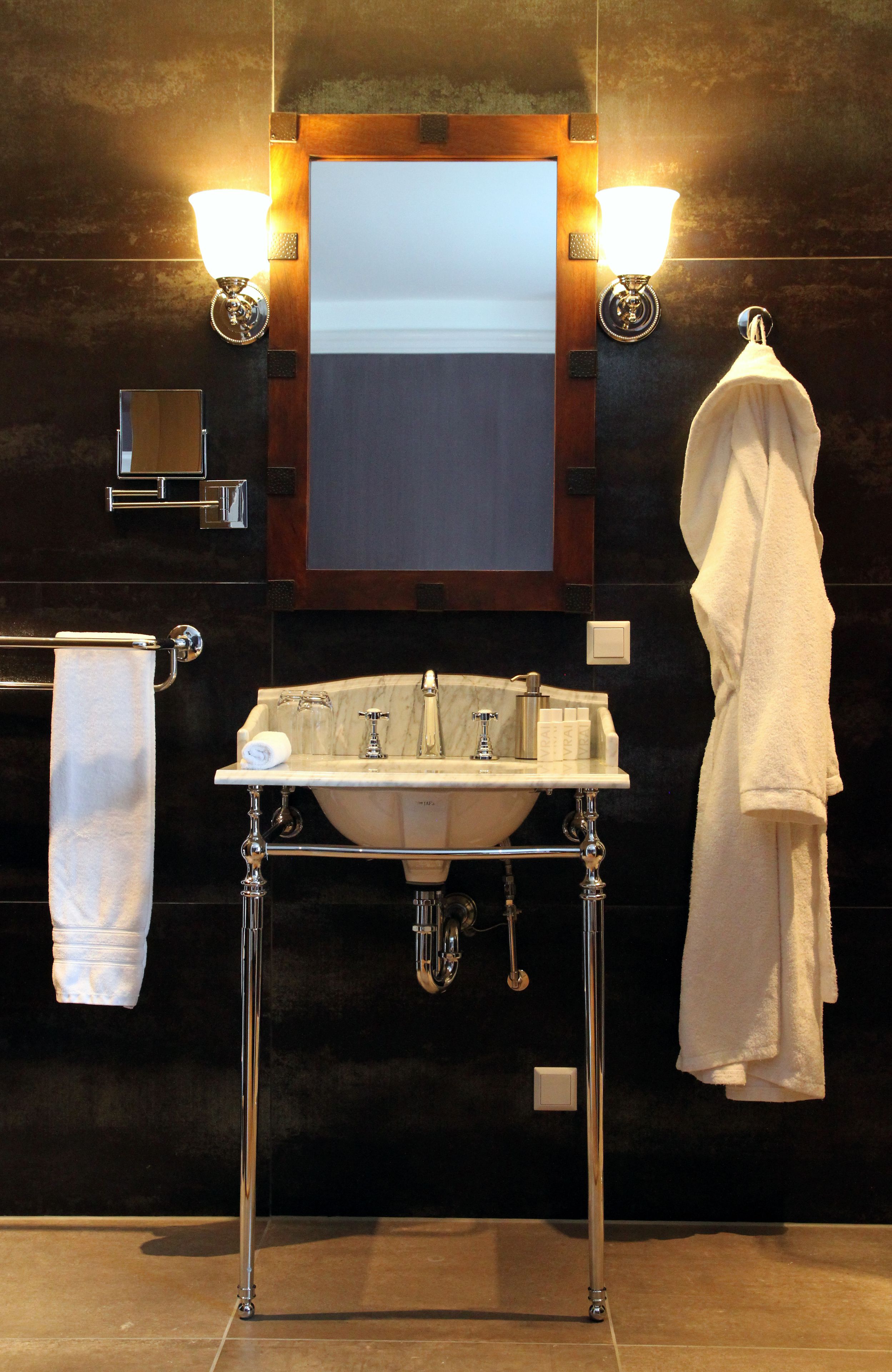 A bathroom with a white sink, two wall-mounted lights, a towel rack, and a mirror above the sink.