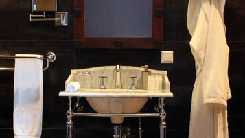 A bathroom with a white sink, two wall-mounted lights, a towel rack, and a mirror above the sink.