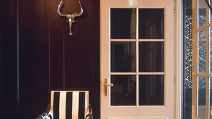 A room with a dark wooden wall, a white door with a glass panel, a striped chair, and a hanging bull's head ornament. - Suitehotel Posthoorn (Monnickendam)
