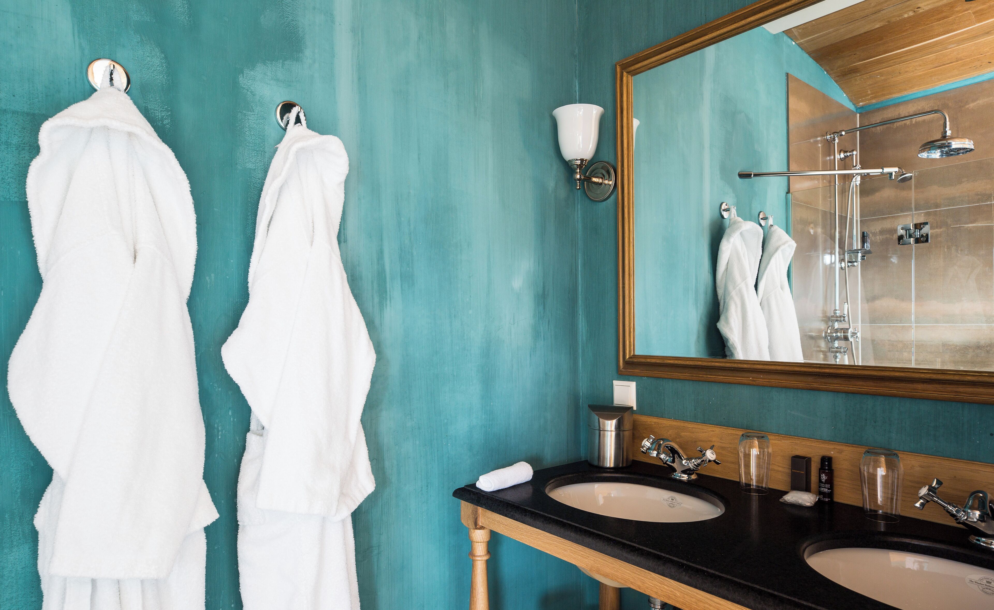 Une salle de bain avec deux lavabos, un miroir et des serviettes accrochées à des crochets.