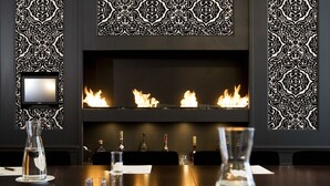 A room with a fireplace, a television mounted on the wall, and several bottles of alcohol on the table. - Suitehotel Posthoorn (Monnickendam)