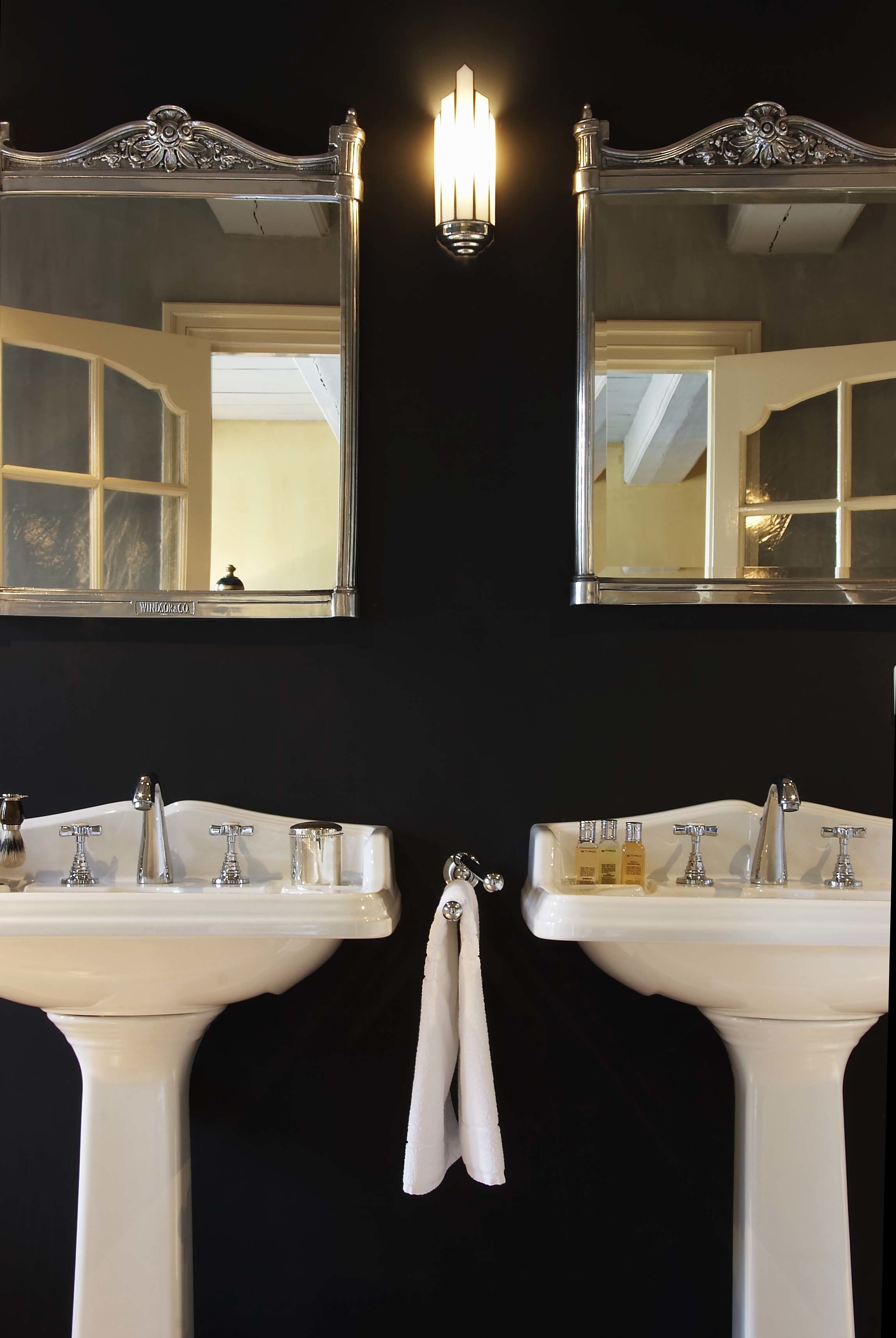 A bathroom with two white sinks, a mirror above each, and a wall-mounted light fixture.