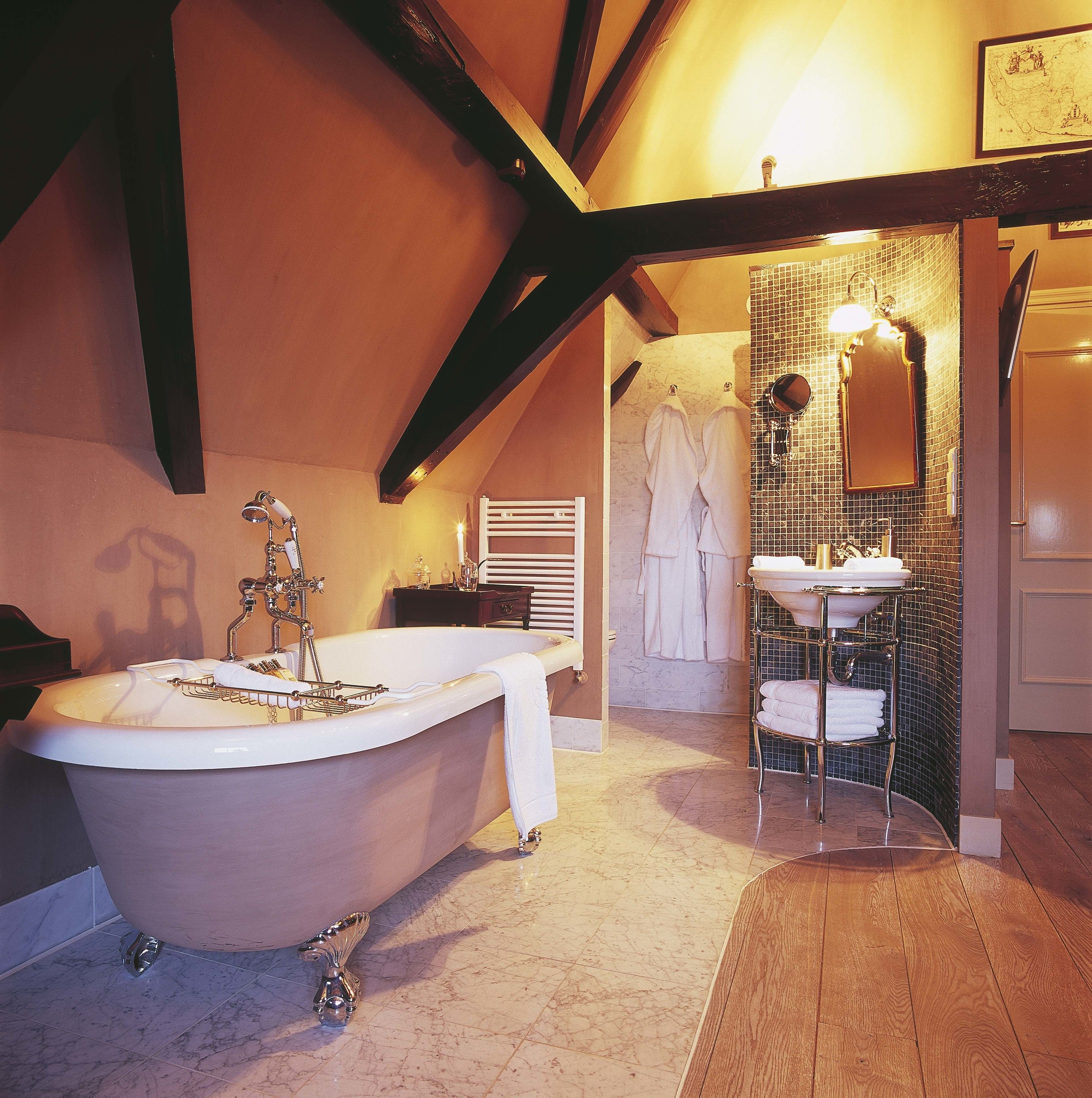A bathroom with a freestanding bathtub, a vanity with a mirror, and a tiled shower area.