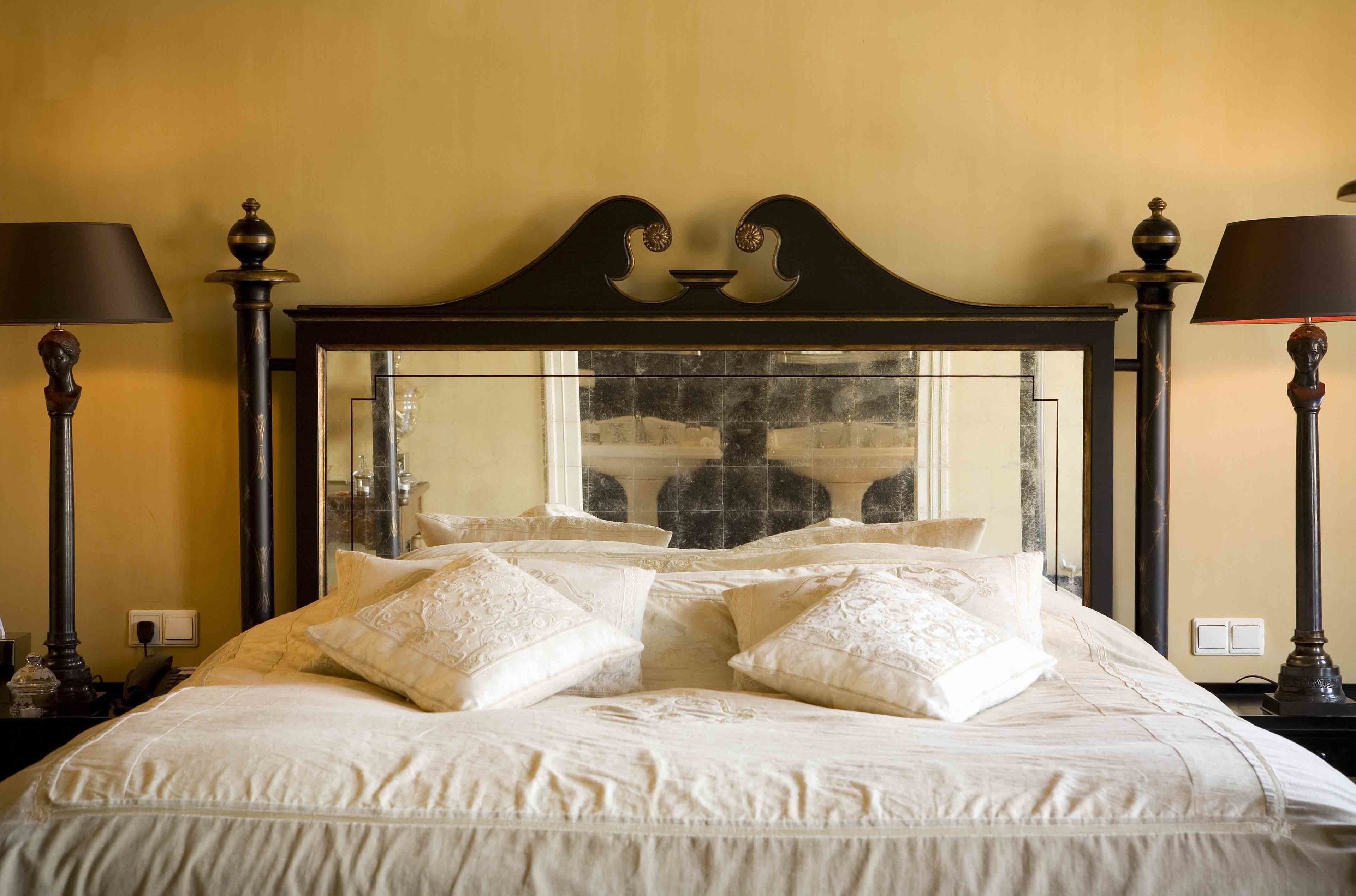 Un lit bien fait, avec une tête de lit agrémentée d’un miroir et d’éléments décoratifs.