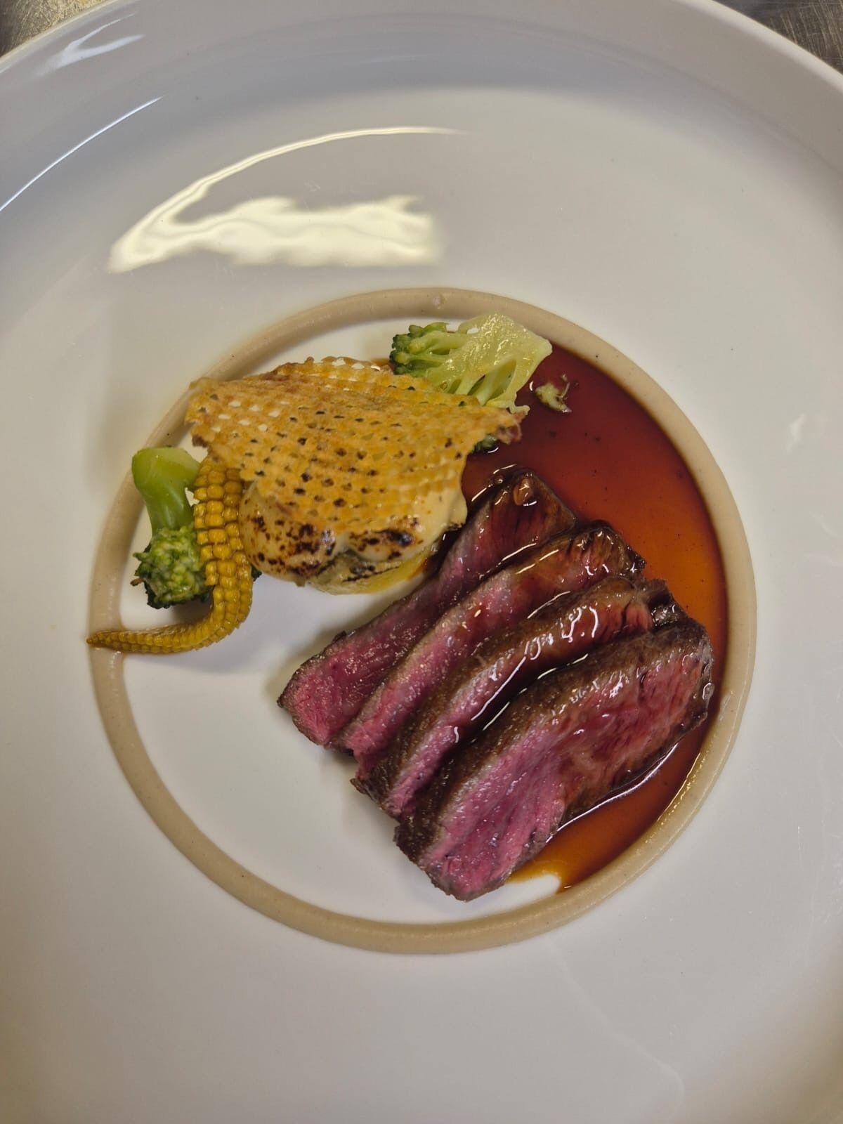 A plate with sliced steak, corn, and broccoli.