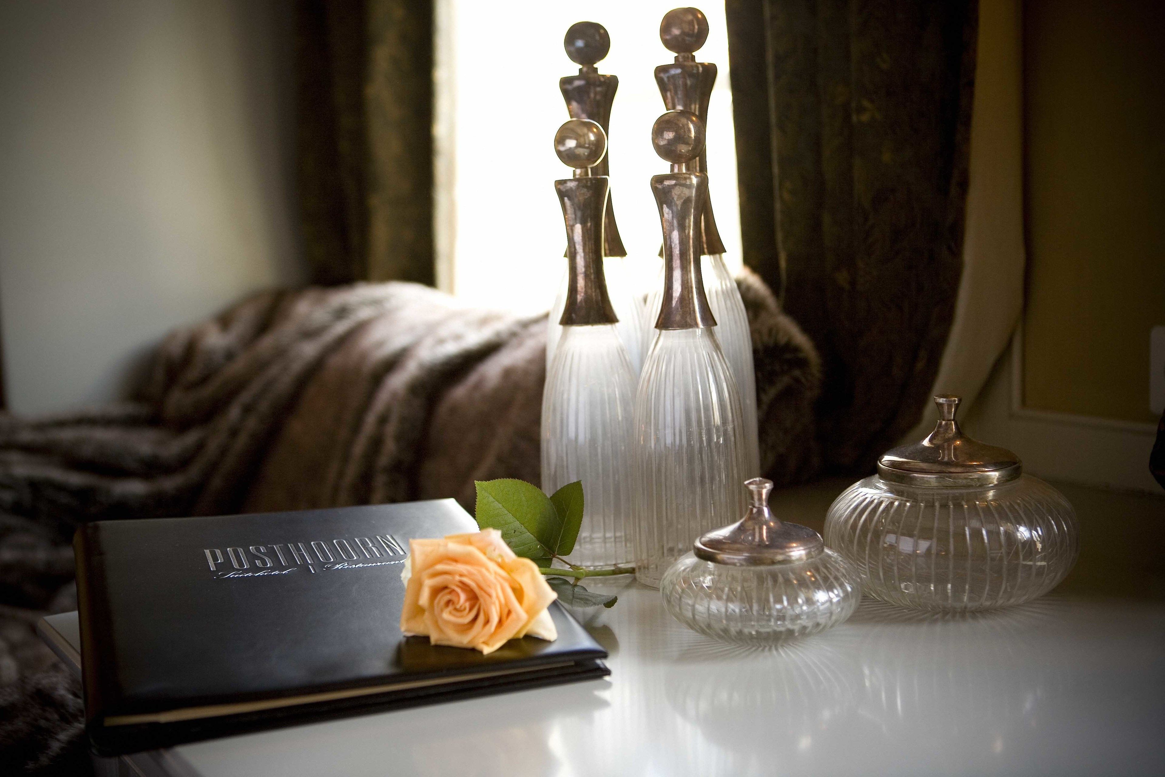 A table with a book, a rose, and three glass vases.
