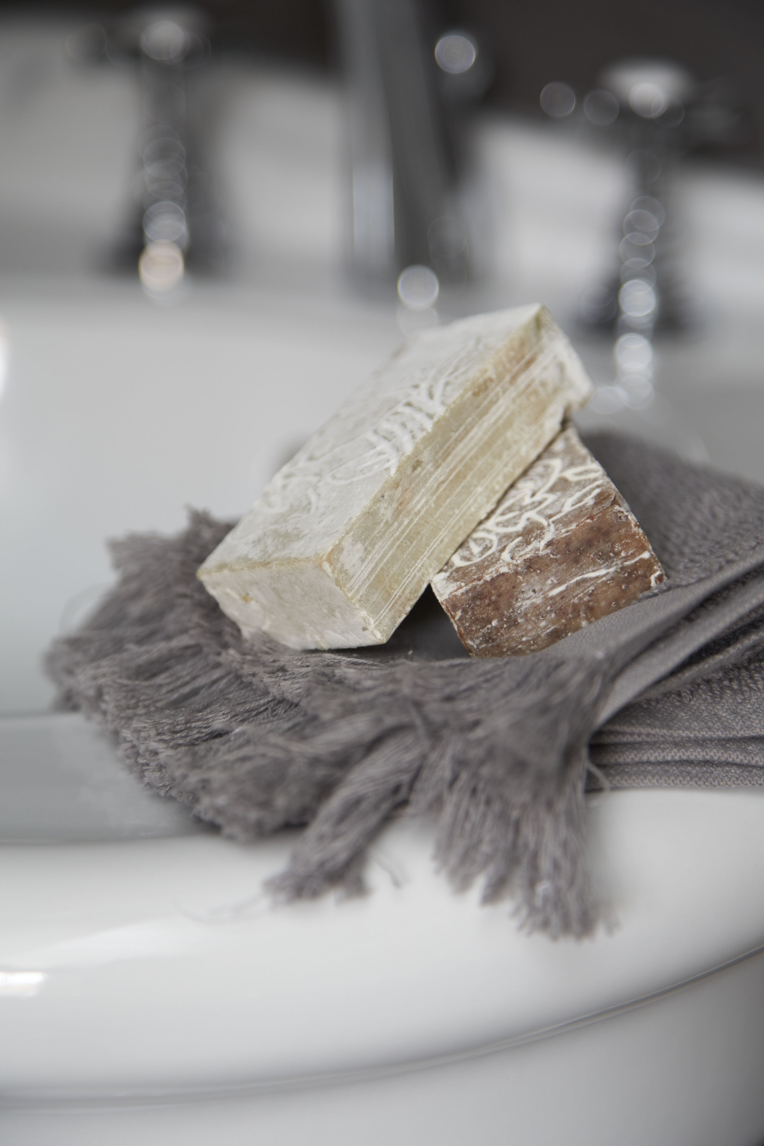A white sink with two bars of soap on a gray towel.