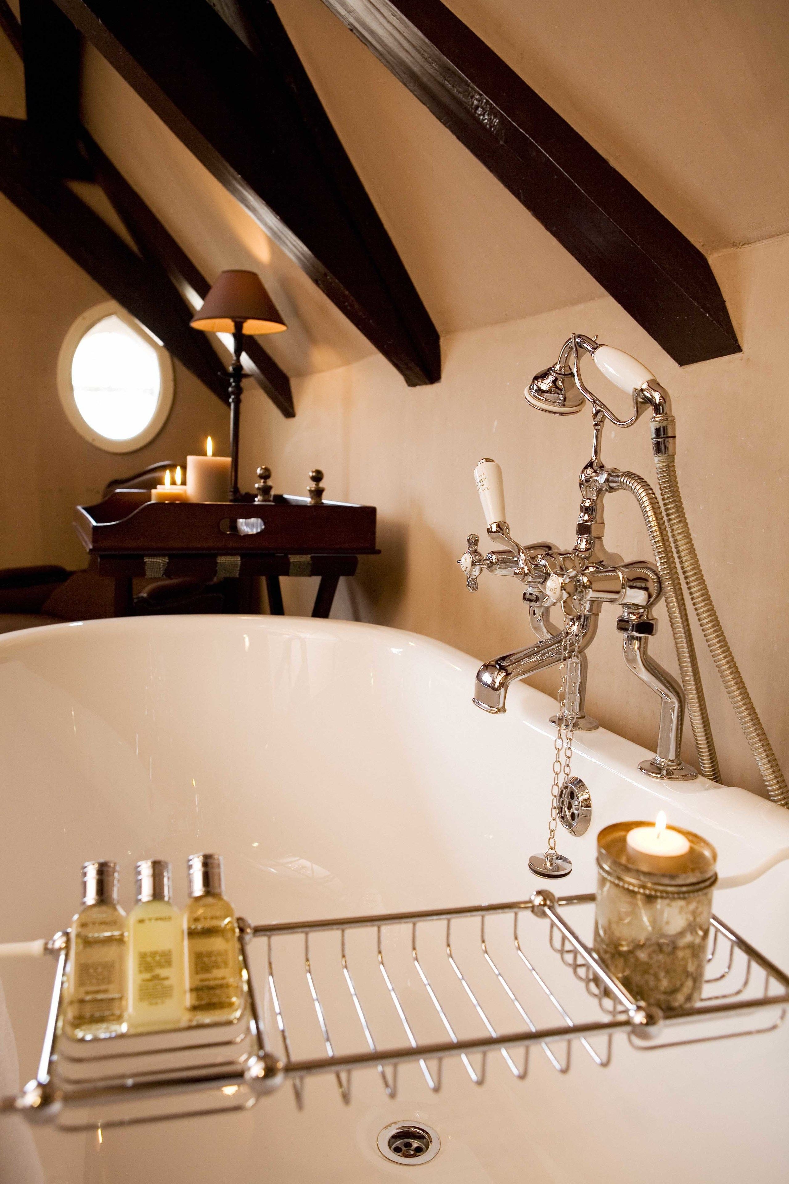 Ein Badezimmer mit einer Badewanne, einer Kerze und einem kleinen Tisch mit Kerzen.